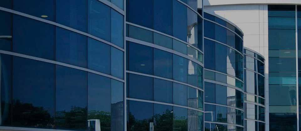 Contemporary office building with reflective blue-tinted glass windows and curved facade